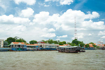 HO CHI MINH CITY, VIETNAM - JUNE 26, 2016: Empty boat with tourists is coming backr the coastline of the river with muddy water to a mooring at vietnamese village. View to the pier and houses at summer sunny dayのeditorial素材