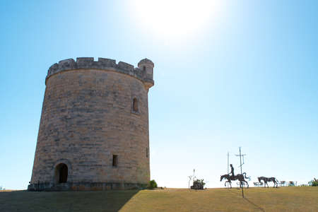 VARADERO, CUBA - FEBRUARY 19, 2013: View of a big ancient stone defensive tower at midday. Nearby an iron statue of the rider on a horse who is going thereのeditorial素材