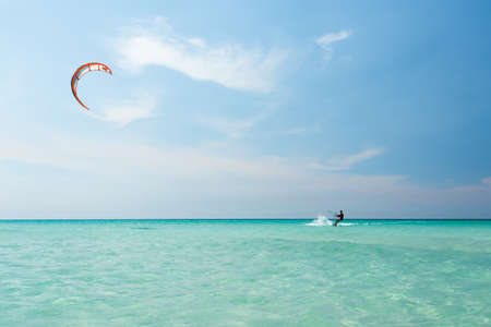 VARADERO, CUBA - APRIL 17, 2015: Athlete young man in a black diving suit is riding a kite on azure water of the Caribbean Sea in hot sunny summer day. Water surface without waves and clear sky without cloudsのeditorial素材