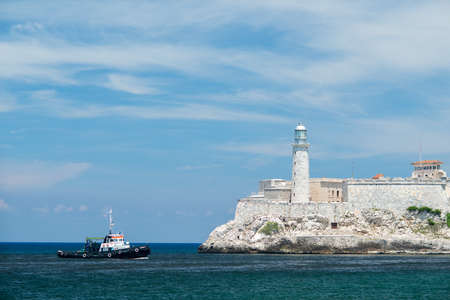 HAVANA, CUBA - SEPTEMBER 04, 2015: View from the seafront Malecon in Havana. Small ship is floating in the Atlantic Ocean. Lighthouse on the fortress is on the entrance to Havana bay at summer sunny day.のeditorial素材