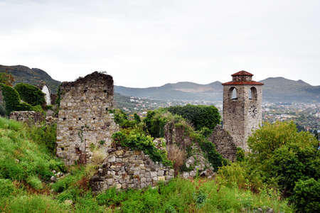 KOTOR, MONTENEGRO â NOVEMBER 13, 2014: View of a stone chapel and fortress ruins in the slope of a mountain. Cityscape and hills at summer day on the backgroundのeditorial素材