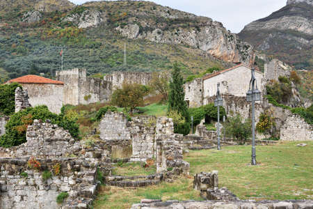 KOTOR, MONTENEGRO - NOVEMBER 13, 2014: View of fortress ruins and village houses on the field at the foot of mountainsのeditorial素材