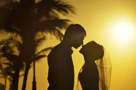 Wedding couple is standing on the beach of the caribbean sea at sunsetの写真素材