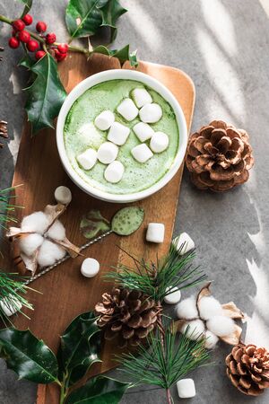 A cup of fragrant and tasty green matcha latte coffee decorated in a Christmas style.
