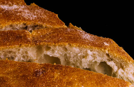 Slices of light wheat bread on dark background with copy space. Macro