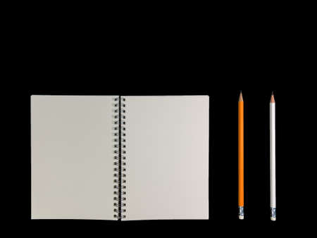 Clear color note book opened for note or lecture note or memo for remine and brown cover whit black head color pencil in white apparel in black background.の写真素材
