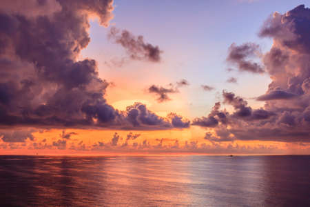Blue sea and red sky with sun red light reflexted in the open sea and boat sailing background.