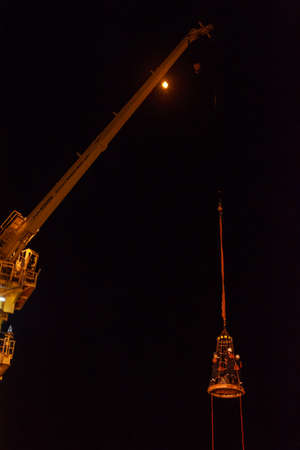 GULF OF THAILAND,SEPTEMBER 29,2017: Offshore oil and gas worker using personal basket for transfer by using crane for lift the passenger between supply boat and platform during night shift.のeditorial素材