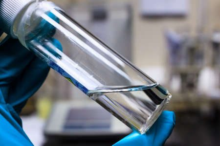 Chemical transparent liquid in clear bottle holding by chemistry hand in green chemical resistance...