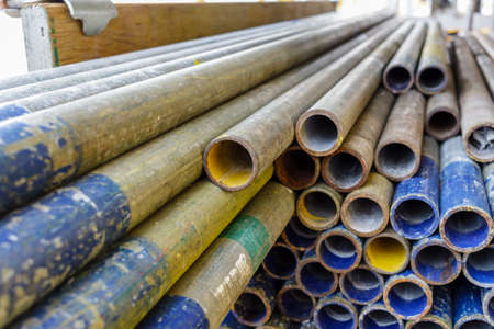 Mental scaffold pipe stack together on scaffold plank wood shelve with blue, green and yellow mark...