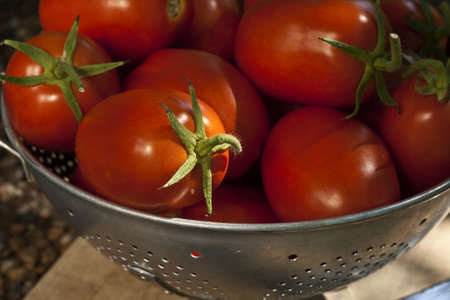 An old aluminum colander full of ripe red Roma type tomatoes の写真素材