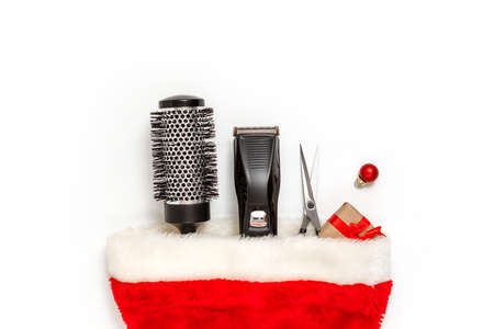 Christmas composition. Hairdressing tools in a Santa Claus hat on a white background. Template for a postcard or information about a hair salon. Flat lay, copy space.の写真素材