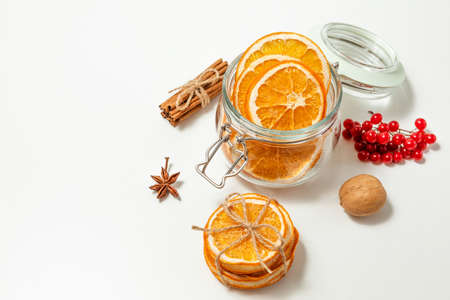 Creative, Christmas and new year, winter composition. dried orange slices in a glass jar, walnuts, viburnum berries and cinnamon sticks on a white background. copy space. selective focusの写真素材