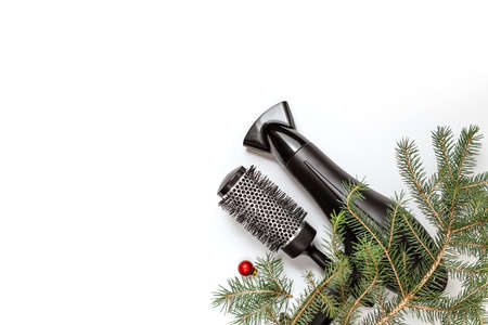Christmas composition. Hairdressing tools and a spruce branch on a white background, hair dryer, comb. Template for a postcard or information about a hair salon. Flat lay, copy spaceの写真素材