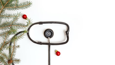 Medical Christmas card with a stethoscope and a spruce branch on a white background. new year's medicine. Copy space. Flat lay.の写真素材