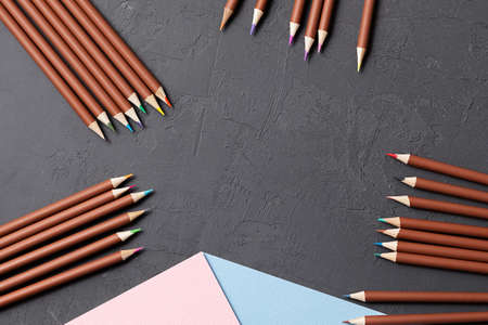 a set of colored pencils, paper sheets for drawing on a gray table. a set for a young artist. the...