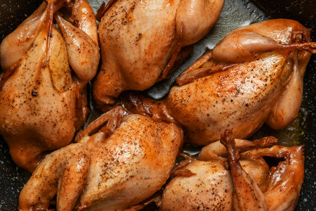 Delicious fried quail carcasses in a frying pan on a dark concrete background. Top view, flat lay. the concept of dietary nutrition.の写真素材