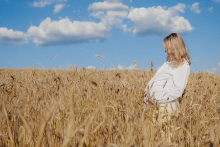 Pregnant girl in white shirt in golden wheat
