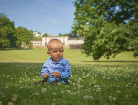a one year old boy sits in a green meadow withの写真素材