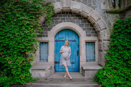 Pregnant girl in beige dress near stone wallの写真素材