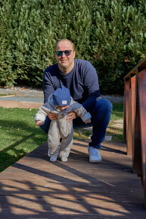 a young dad and holds his six-month-old son on a