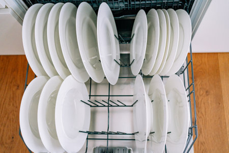 open dishwasher with clean white platesの写真素材