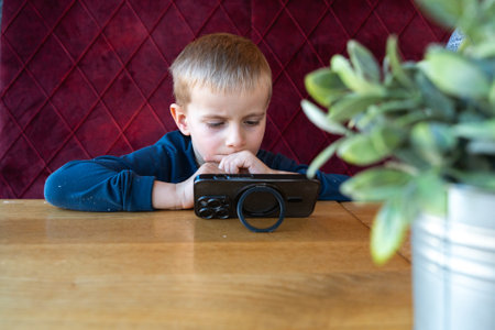A 4-5-year-old European boy sits at the tableの写真素材