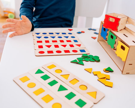 A child carefully places colorful wooden geometricの写真素材