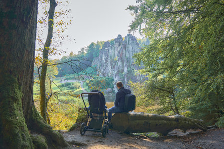dad sits on a fallen tree trunk next to a baby inの写真素材