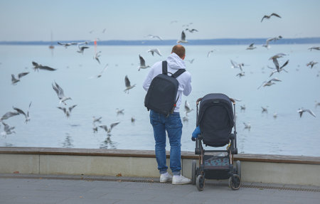 Daddy stands next to the stroller with his back toの写真素材