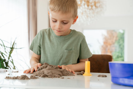 A child molds kinetic sand at the tableの写真素材