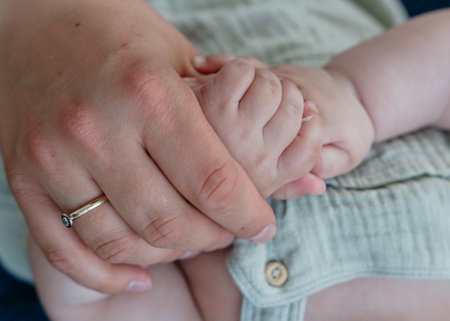 Mother and baby holding hands in a loving gestureの写真素材