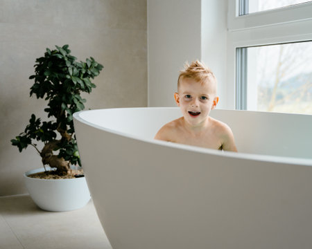 In a calm, sunlit bathroom, a young child enjoysの写真素材