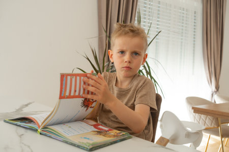 Child Reading a Book with a Confused Expressionの写真素材