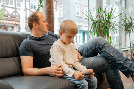 Father and Son Relaxing Together Using Smartphone