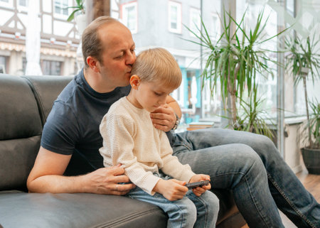 Father Kissing Son While Playing On Phoneの写真素材