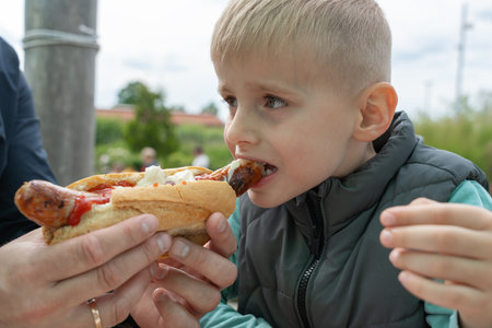Young Boy Enjoying a Hot Dog Outdoors withの写真素材