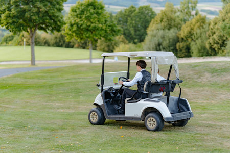 Young Boy Driving Golf Cart on Lush Green Golfの写真素材