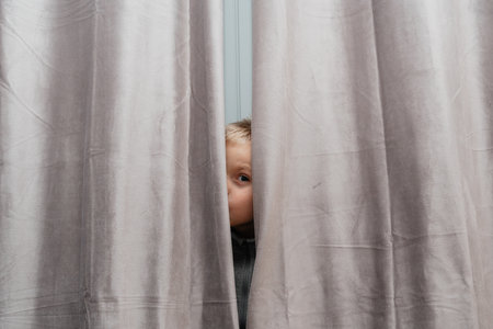 Child Peeks from Curtain Edgeの写真素材