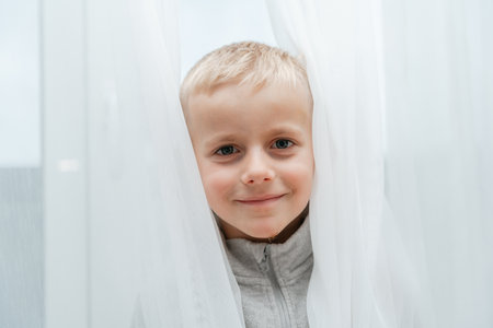 Child framed by translucent drapery, smilingの写真素材