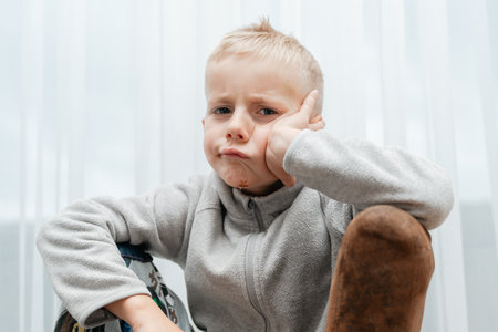 Child leans on hand in contemplative, perhapsの写真素材