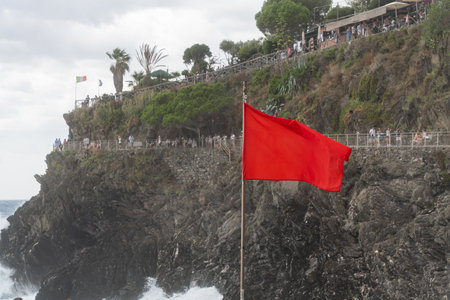 Red Warning Flag on Rocky Coastの写真素材
