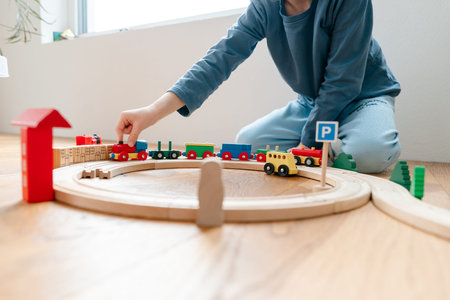 Adult playing with toddler using wooden railwayの写真素材