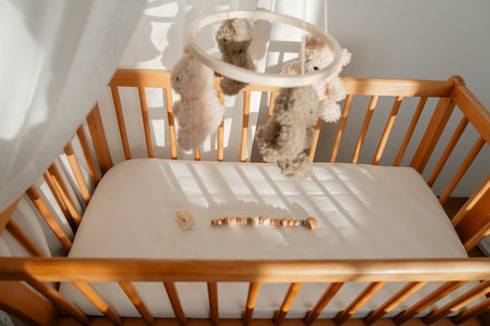 Wooden baby crib with hanging mobile in bright