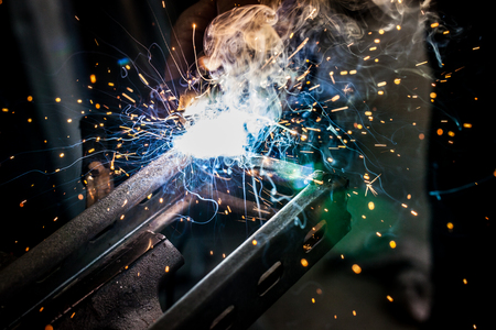 Metal welding with sparks and smoke on dark background