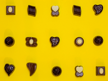 Gourmet chocolates pattern on vivid yellow background flat layの写真素材