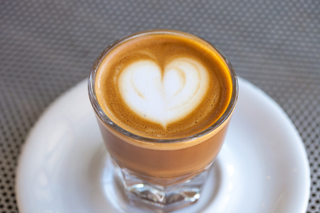 Top view of cortado coffee in a glass with the foam in shape of heart