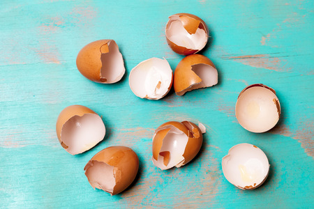 Top view of egg shells on wooden teal green rustic background, flat lay design with egg shells