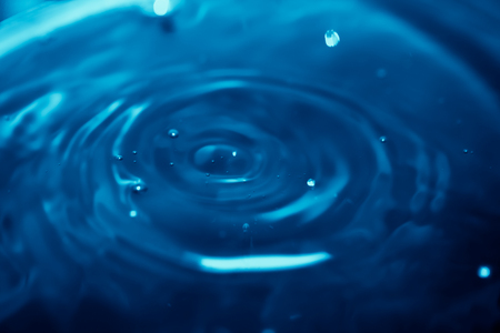Abstract background with blue liquid ripples and drops, and light reflection, blurred backgroundの写真素材