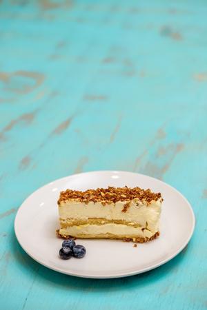 Almond cake slice on a white plate on a rustic green table, with copy space